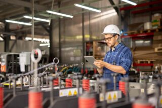 Man using a tablet for quality management in a factory